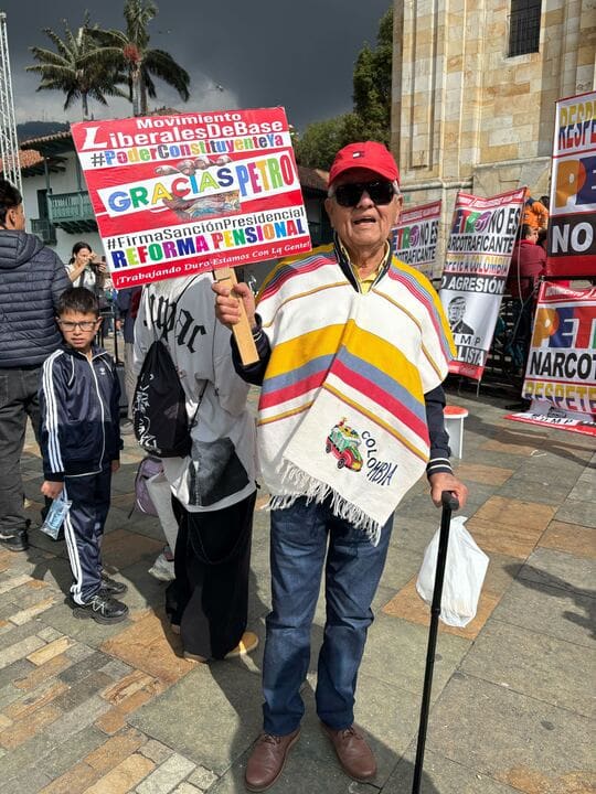 Jesid Flores holds a sign that reads "Movimiento Liberales De Base #PoderConstituyenteYa Gracias Petro #FirmaSancionPresidencial Reforma Pensional !Trabajando Duro Estamas Con La Gente!