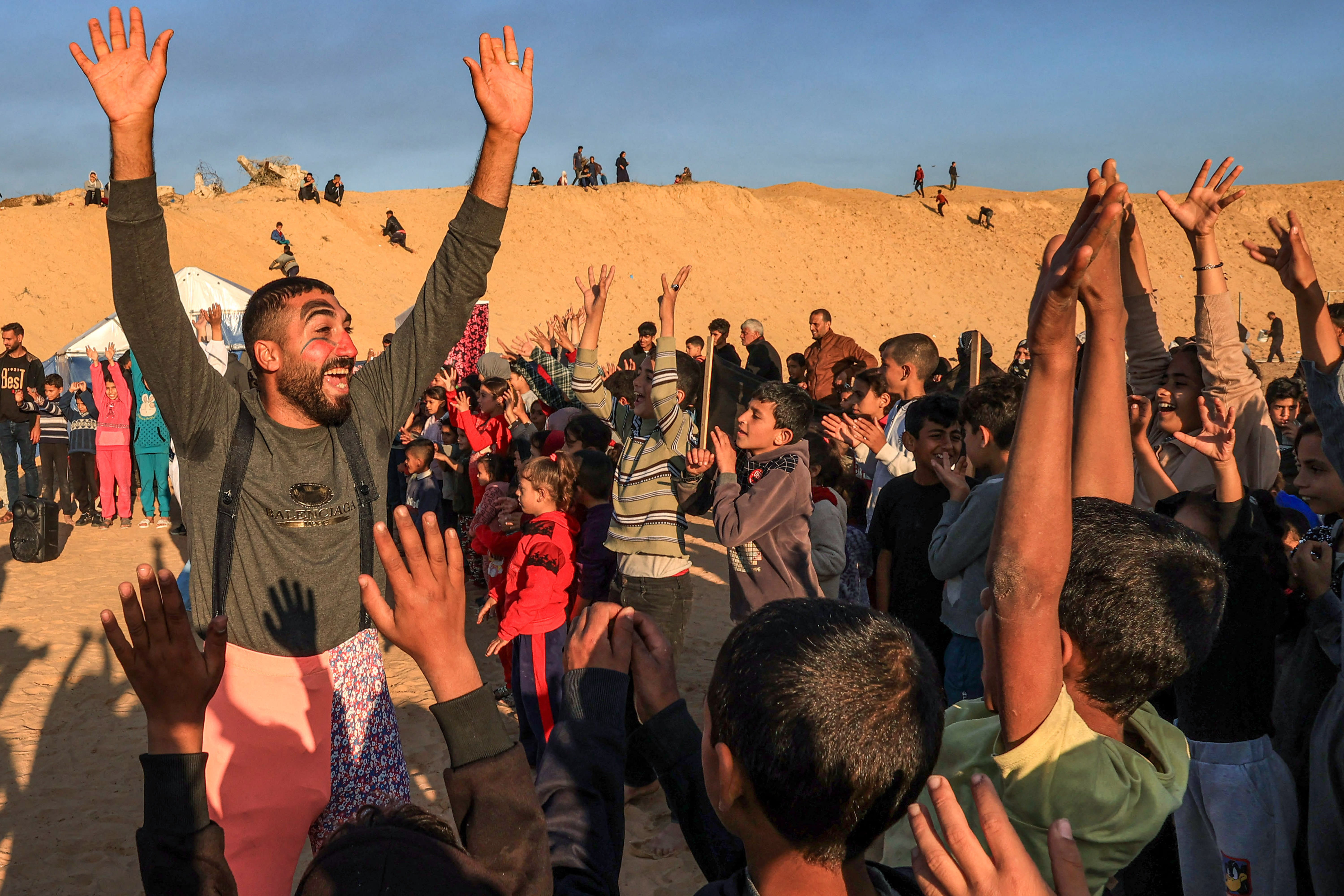 A man dressed as a clown performs for children participating in an activity aimed to support their mental health, amid continuing battles between Israel and the militant group Hamas, in Rafah in the southern Gaza Strip on December 18, 2023.