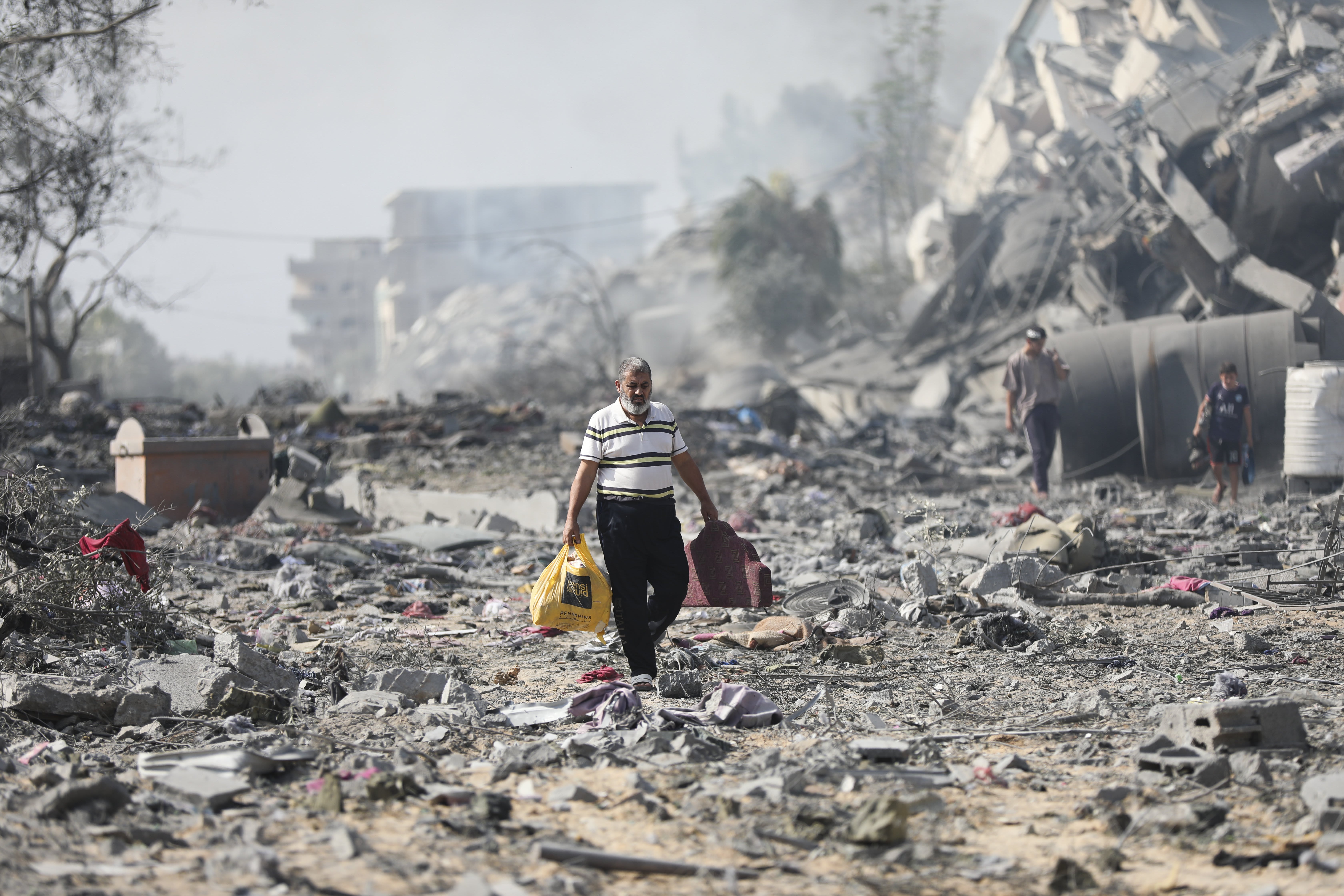 A Palestinian man walks through debris next to buildings destroyed in an Israeli bombardment on al-Zahra, on the outskirts of Gaza City, Friday, Oct. 20, 2023.