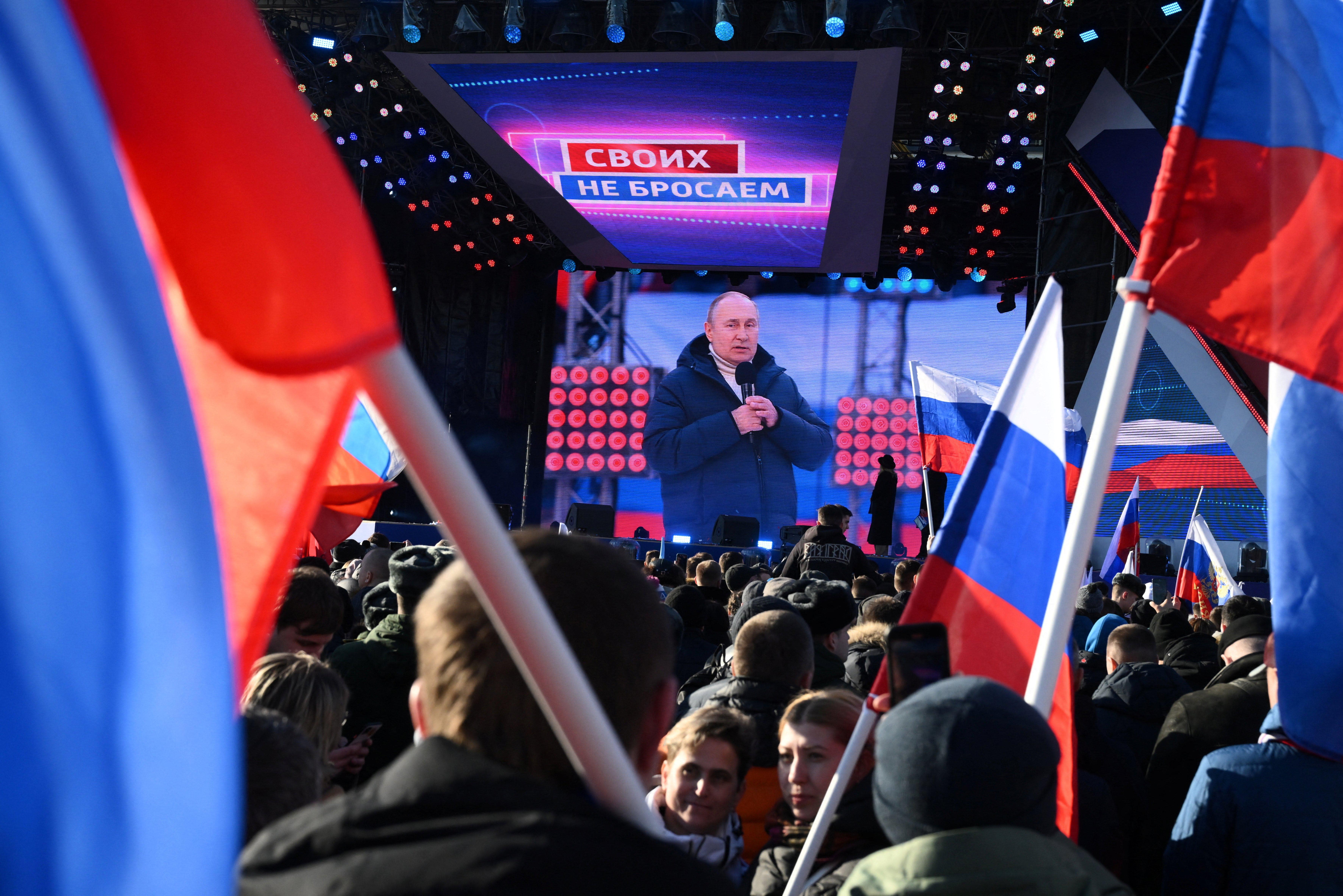 People watch a broadcast of Russian President Vladimir Putin's speech during a concert marking the eighth anniversary of Russia's annexation of Crimea outside Luzhniki Stadium in Moscow on Friday.