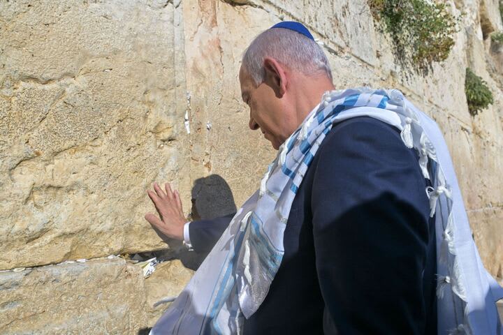 Benjamin Netanyahu holds a note containing a prayer into the Western Wall that says: “The people have risen as a lion. Am Israel Chai!”