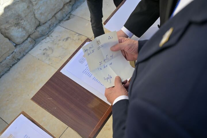 Benjamin Netanyahu holds a note containing a prayer into the Western Wall that says: “The people have risen as a lion. Am Israel Chai!”
