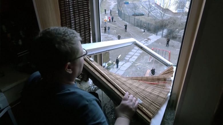 Defiant Kyiv resident sings national anthem as she clears apartment debris