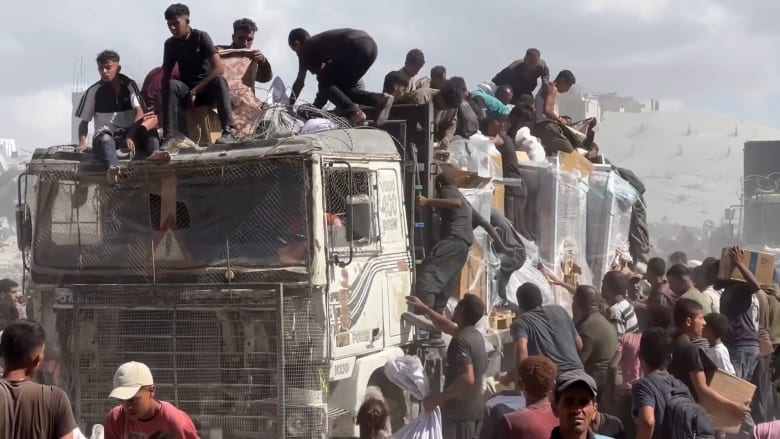Palestinians crowd onto aid trucks moving through Gaza
