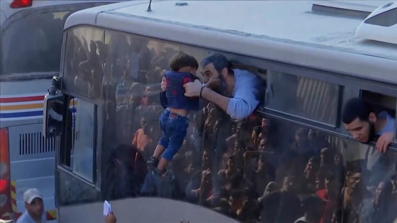 Child embraced by freed Palestinian prisoner as buses arrive in Gaza