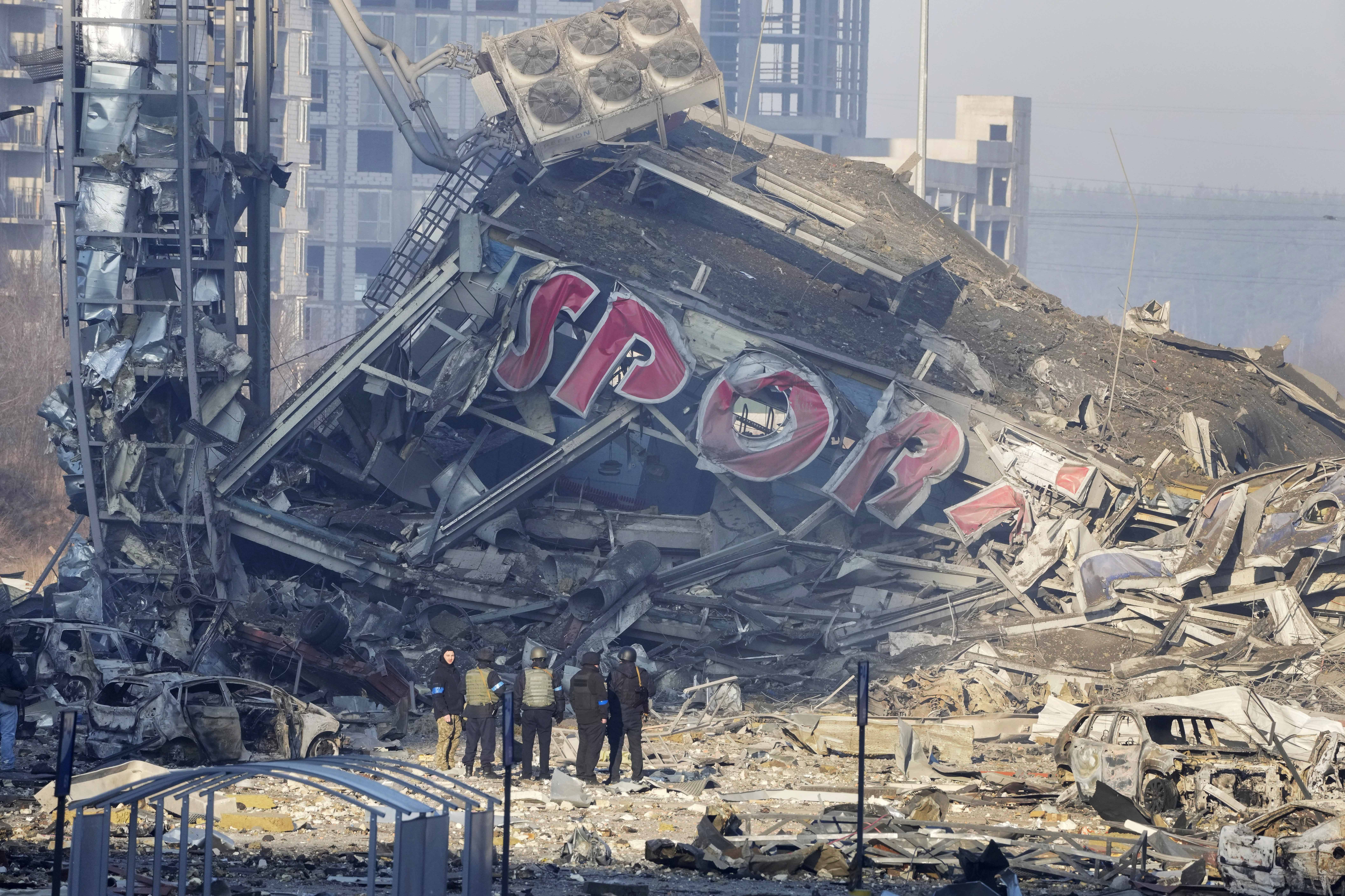 People examine the damage after shelling of a shopping center, in Kyiv, Ukraine, Monday.