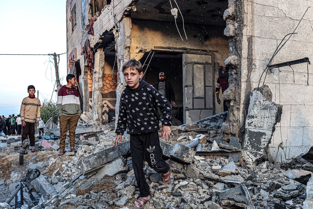 People walk through the rubble of a building heavily damaged by Israeli bombardment, in Rafah, Gaza