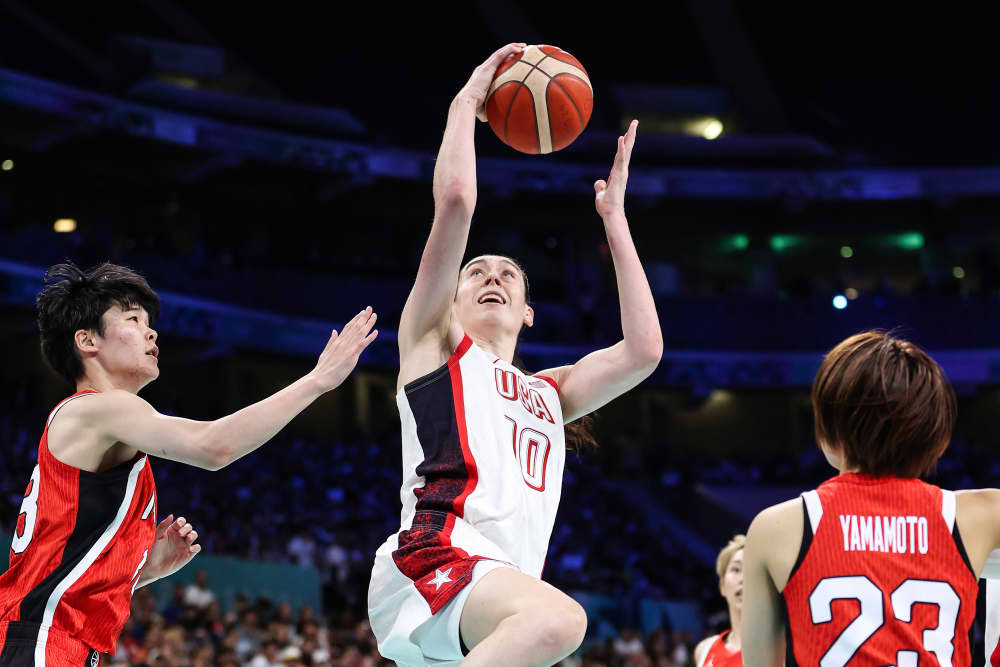 Breanna Stewart jumps to make a basket between two opposing players