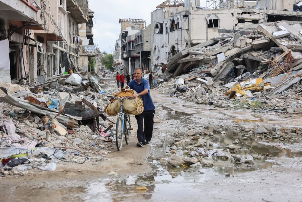 A man pushes his bicycle past rubble in the Shujaiya neighborhood of Gaza City on Oct. 7, 2024.