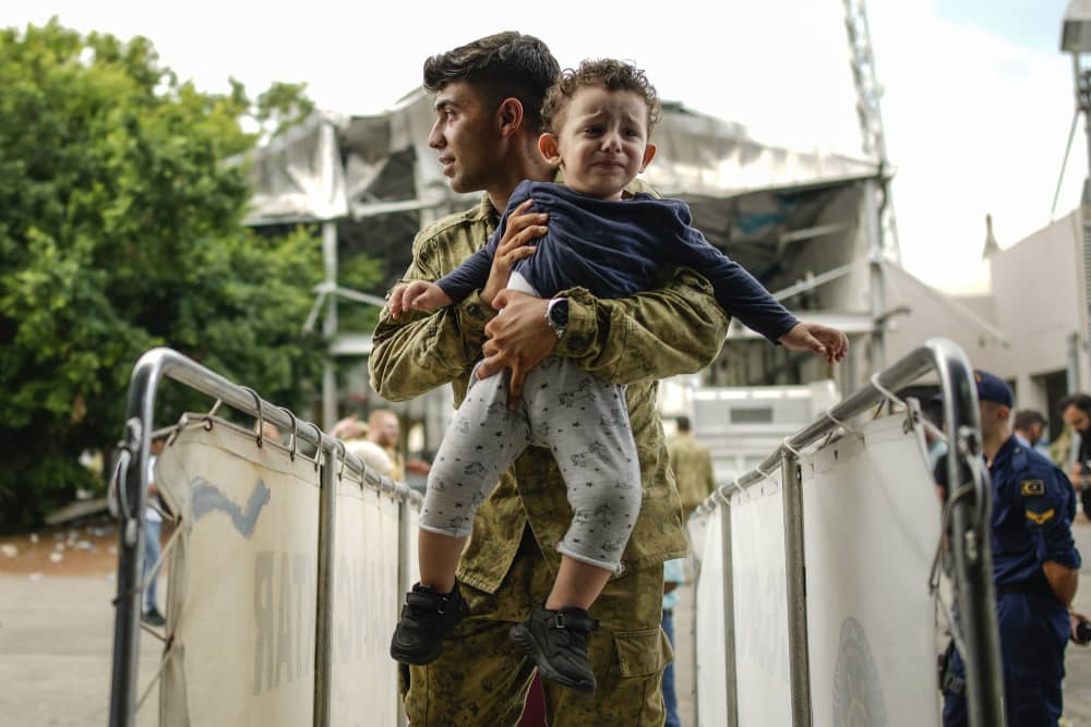 A Turkish soldier carries a child on board of a Turkish military ship as hundreds of people, mostly Turkish citizens, are evacuated from Lebanon to Turkey, in Beirut's port Oct. 10, 2024. 