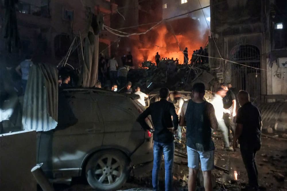 Lebanese civil defense members and others look at the site of an Israeli airstrike on the Basta neighborhood of Beirut