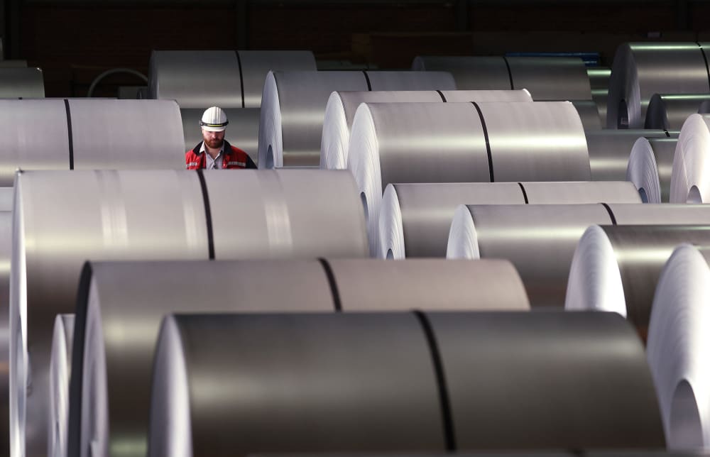 A worker walks among coils of finished steel at a steel plant on April 9, 2025 in Duisburg, Germany. 