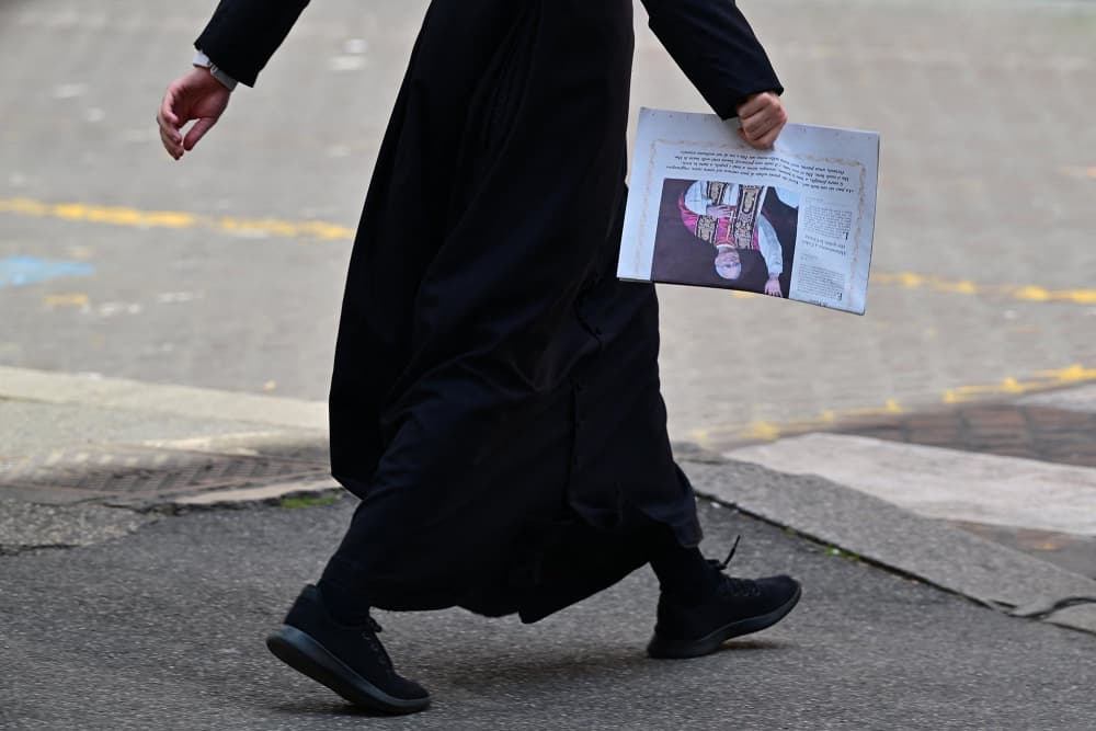 A pedestrian walks with an edition of L'Osservatore Romano newspaper with the front page picture of newly elected pope Leo XIV in Rome on May 9, 2025. 