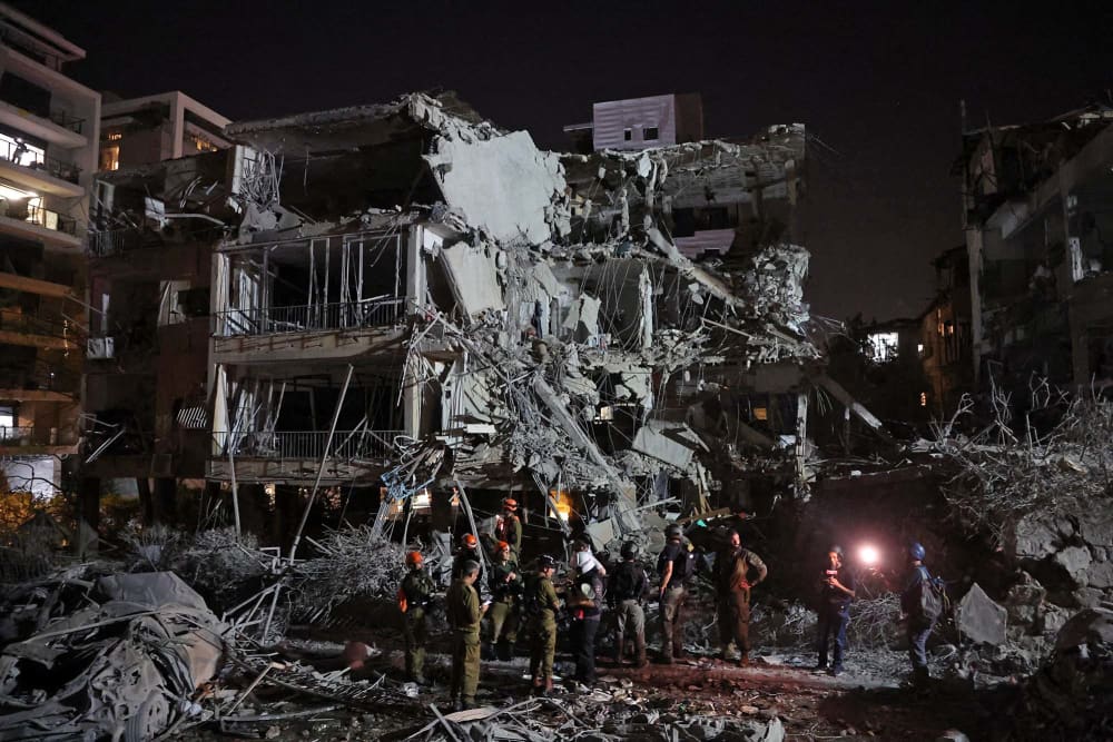 Israeli troops and first responders gather in front of a building hit by an Iranian missile in Tel Aviv on June 13, 2025. 
