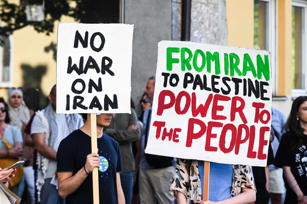 Demonstrators hold signs reading "No War on Iran" and "From Iran to Palestine Power to the People"