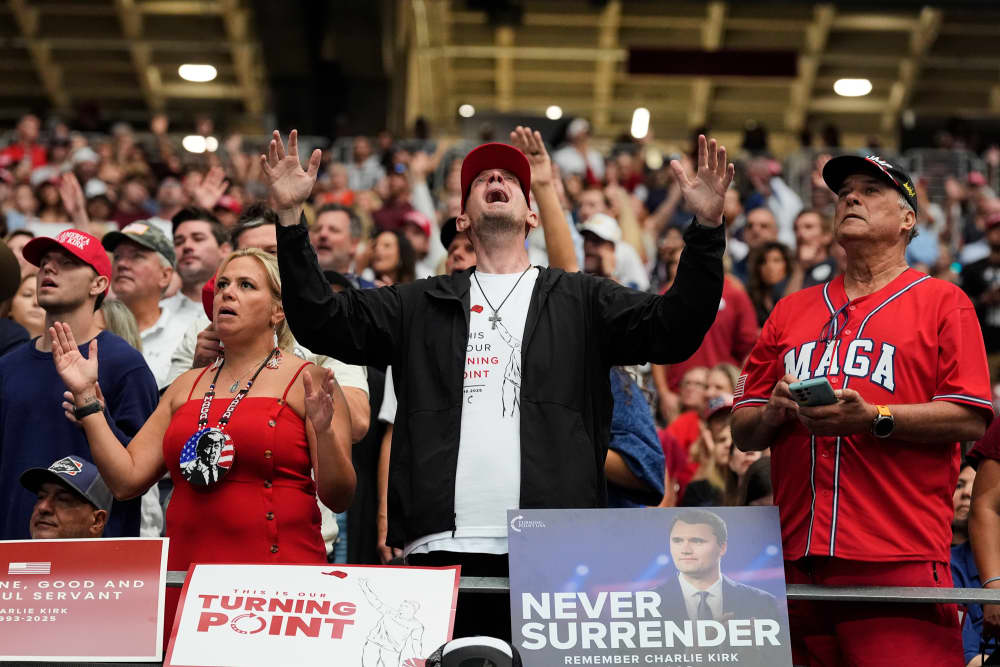 People pray in a crowd in a stadium