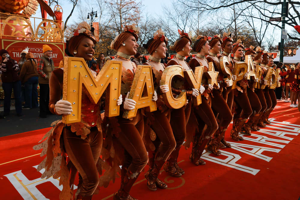 Dancers hold letters that spell out Macy's Day Parade outside