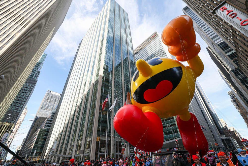A large Pac-Man balloon floats down the street
