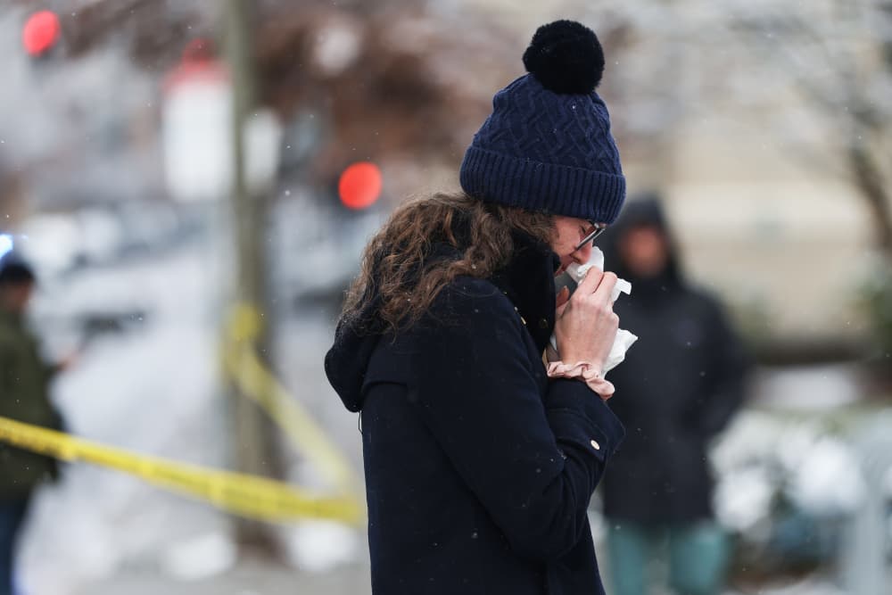 A woman cries outside, placing tissue on her face