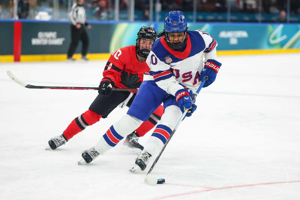 Laila Edwars controls the puck on the ice in front of an opposing team player
