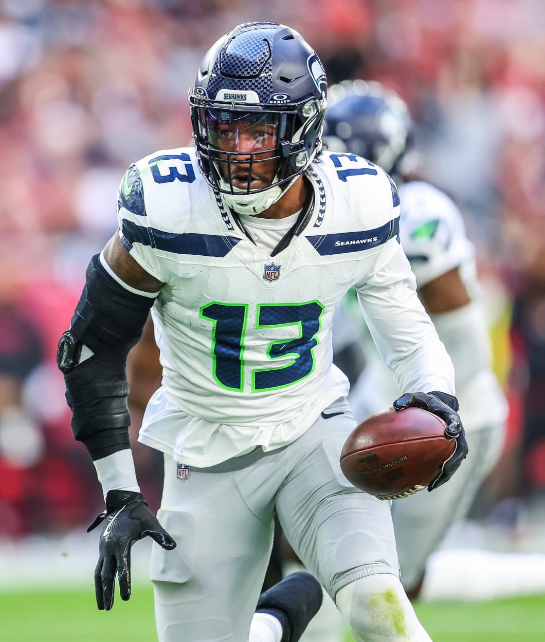 Ernest Jones IV carries a football in his left hand while running on the field during a game.