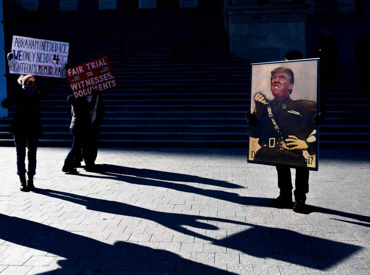 Image: Protesters hold signs near the Capitol during the impeachment trial of President Donald Trump on Jan. 29, 2020.