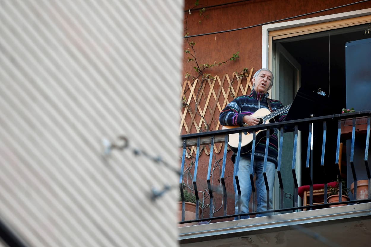 Image: A man plays the guitar on his balcony in Milan on March 15, 2020.