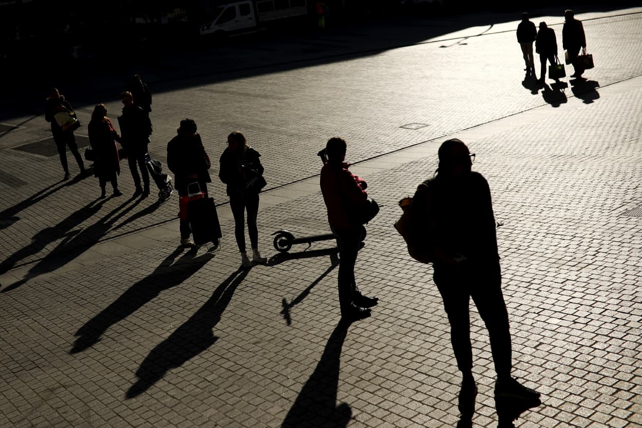 Image: People stand apart while waiting to enter a supermarket in Brussels on March 18, 2020.