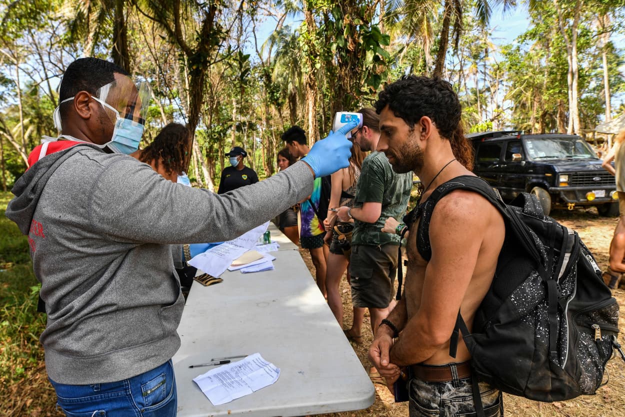 Image: A health worker checks the temperature of an attendee of the Tribal Gathering festival rock in Cuango, Colon province, Panama