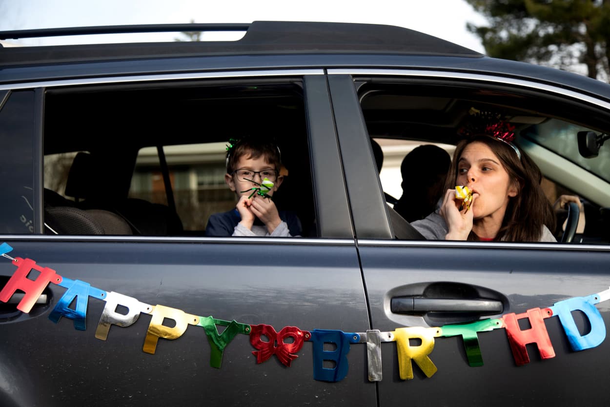 Image: Dana Baer, right, and her son, Jacob, wish Avery Slutsky a happy birthday during a drive-by birthday celebration to maintain social distancing in West Bloomfield Township, Mich., on March 24, 2020.