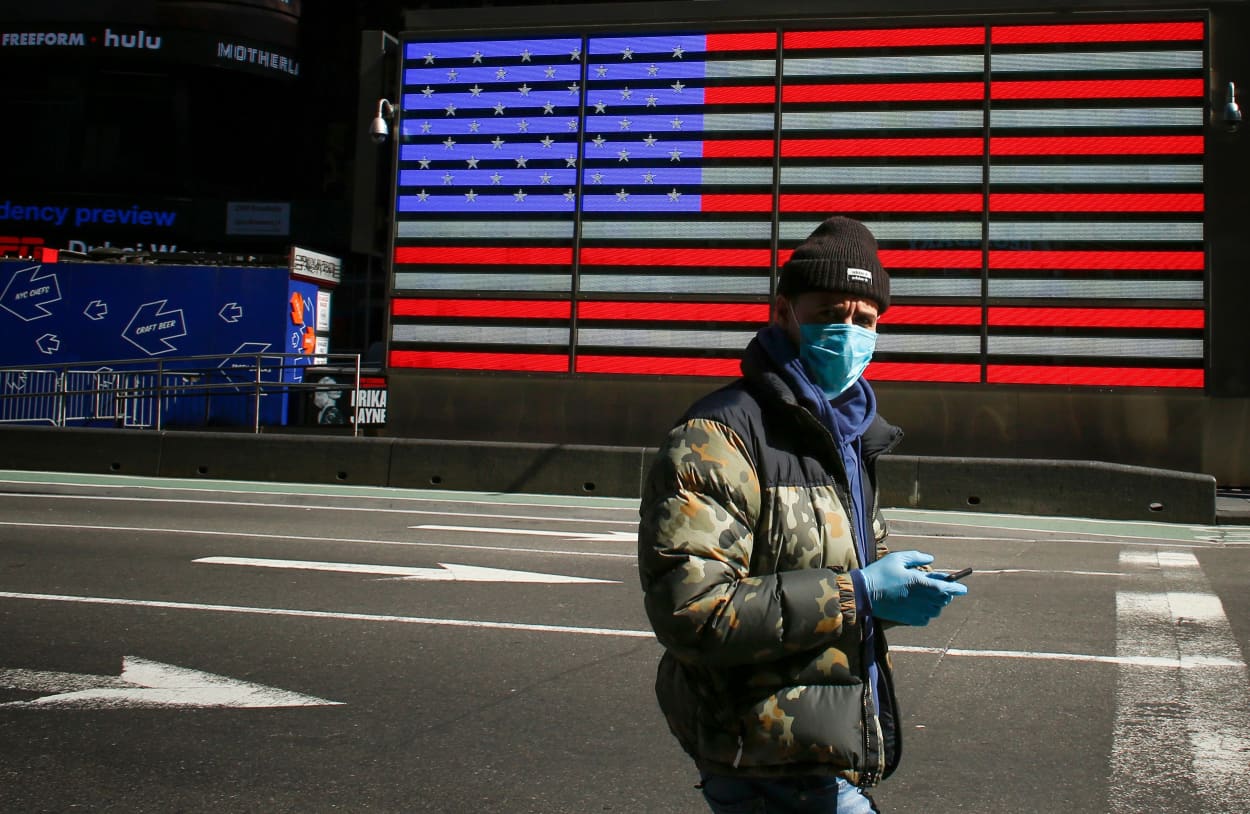 Image: A man wearing a mask checks his phone in Times Square in New York on March 22, 2020.