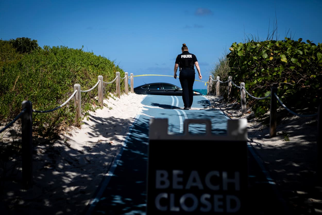 Image: A police officer walks toward a closed portion of South Beach, Fla., on March 19, 2020.