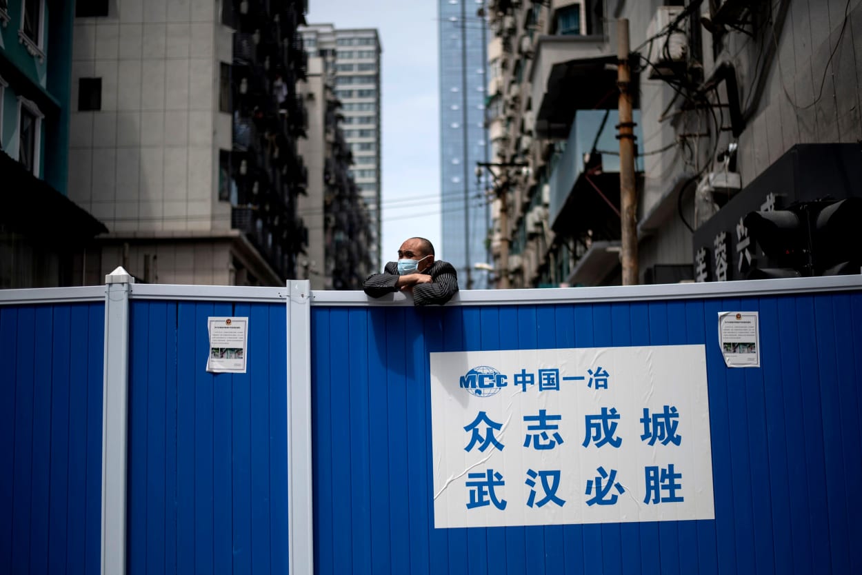 Image: A man looks over a barricade on a street in Wuhan on April 14, 2020.