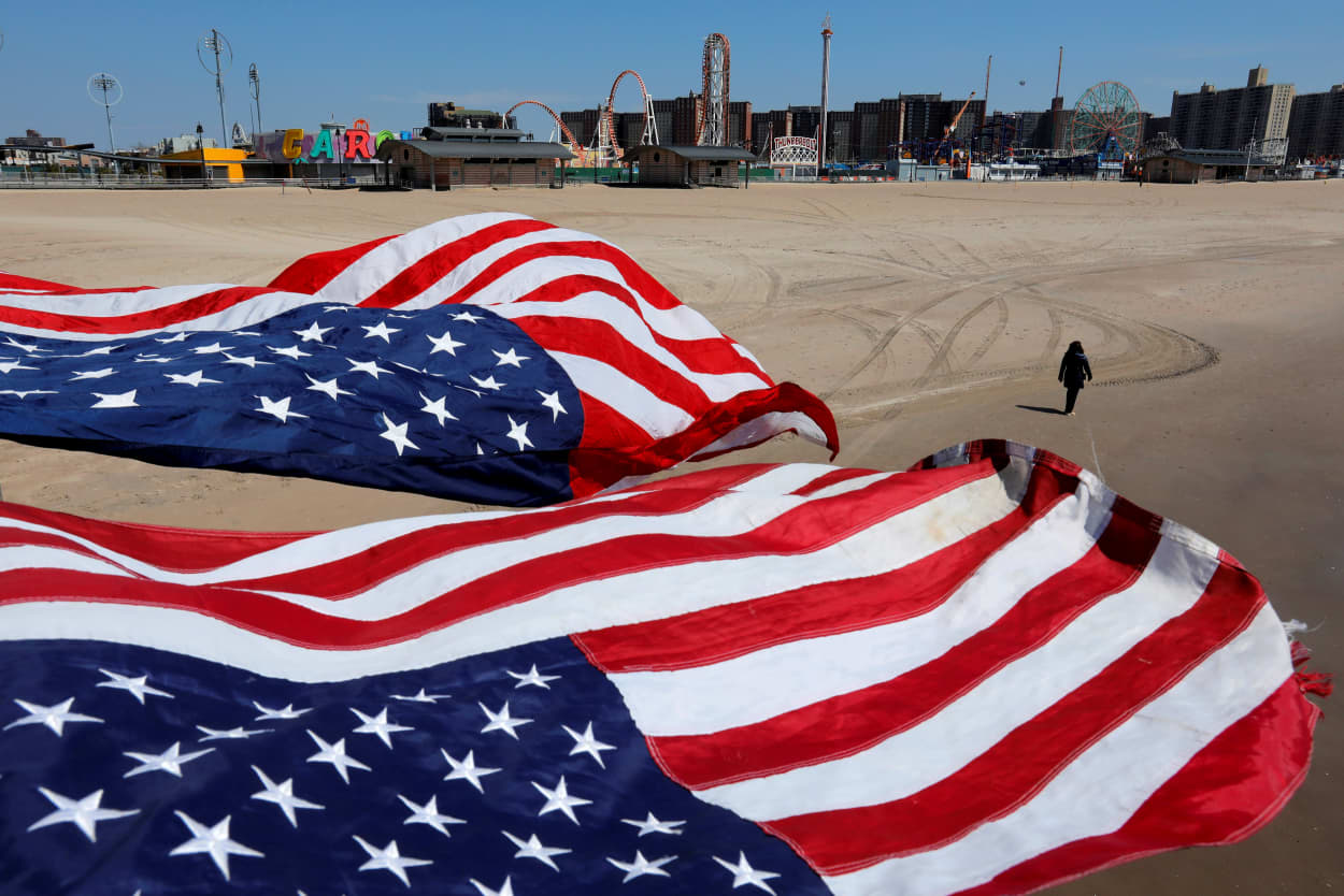 Image: A person walks along the sand at the empty Coney Island beach in Brooklyn, N.Y., on April 19, 2020.