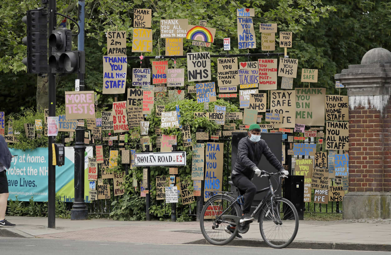 A cyclist passes signs supporting the National Health Service in a display coordinated by artist and local resident Peter Liversidge in east London, on April 27, 2020.