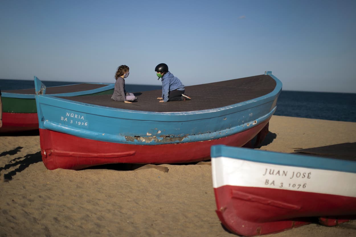 Image: Two children wearing face masks sit on top of a boat in a beach in Badalona, near Barcelona, Spain on Tuesday.