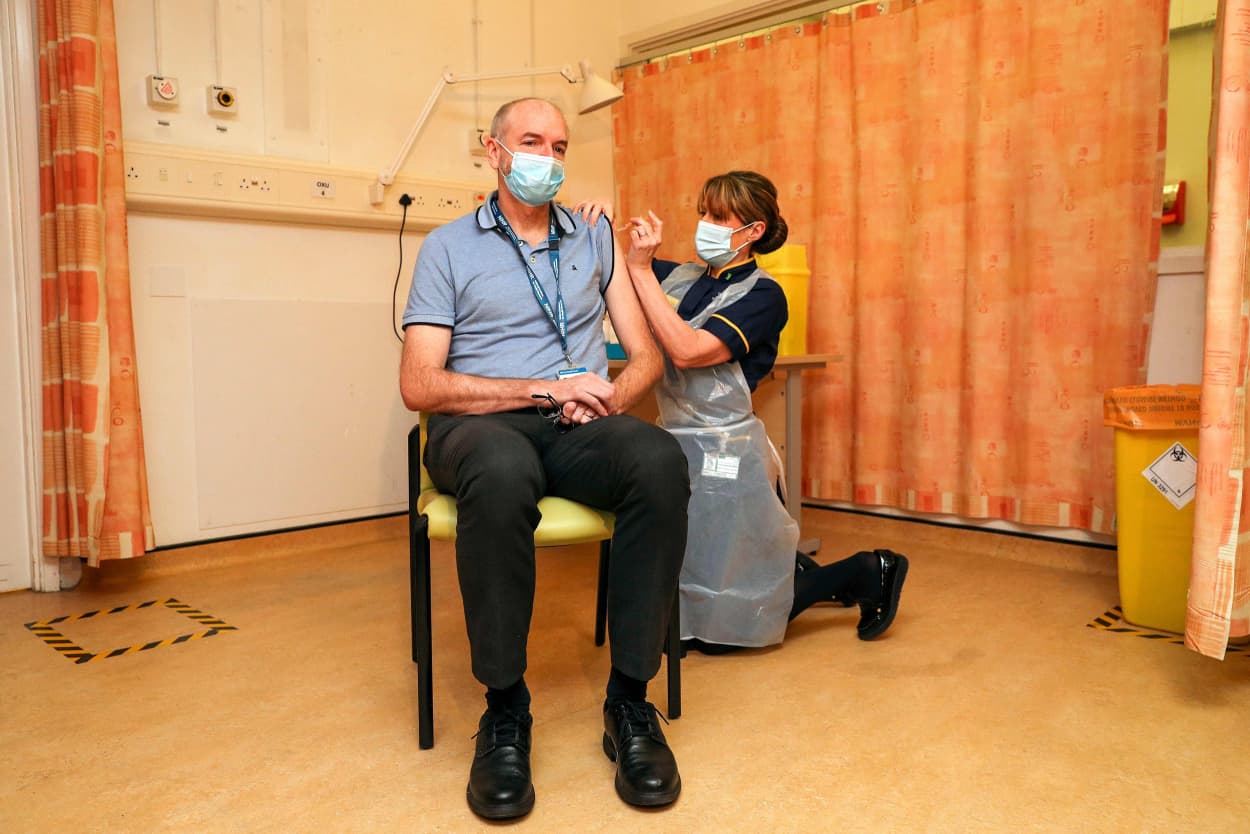 Image: Andrew Pollard, Director of the Oxford Vaccine Group, and a professor of pediatric infection and immunity receives the Oxford University/AstraZeneca Covid-19 vaccine from nurse Sam Foster at the Churchill Hospital in Oxford, southwest England