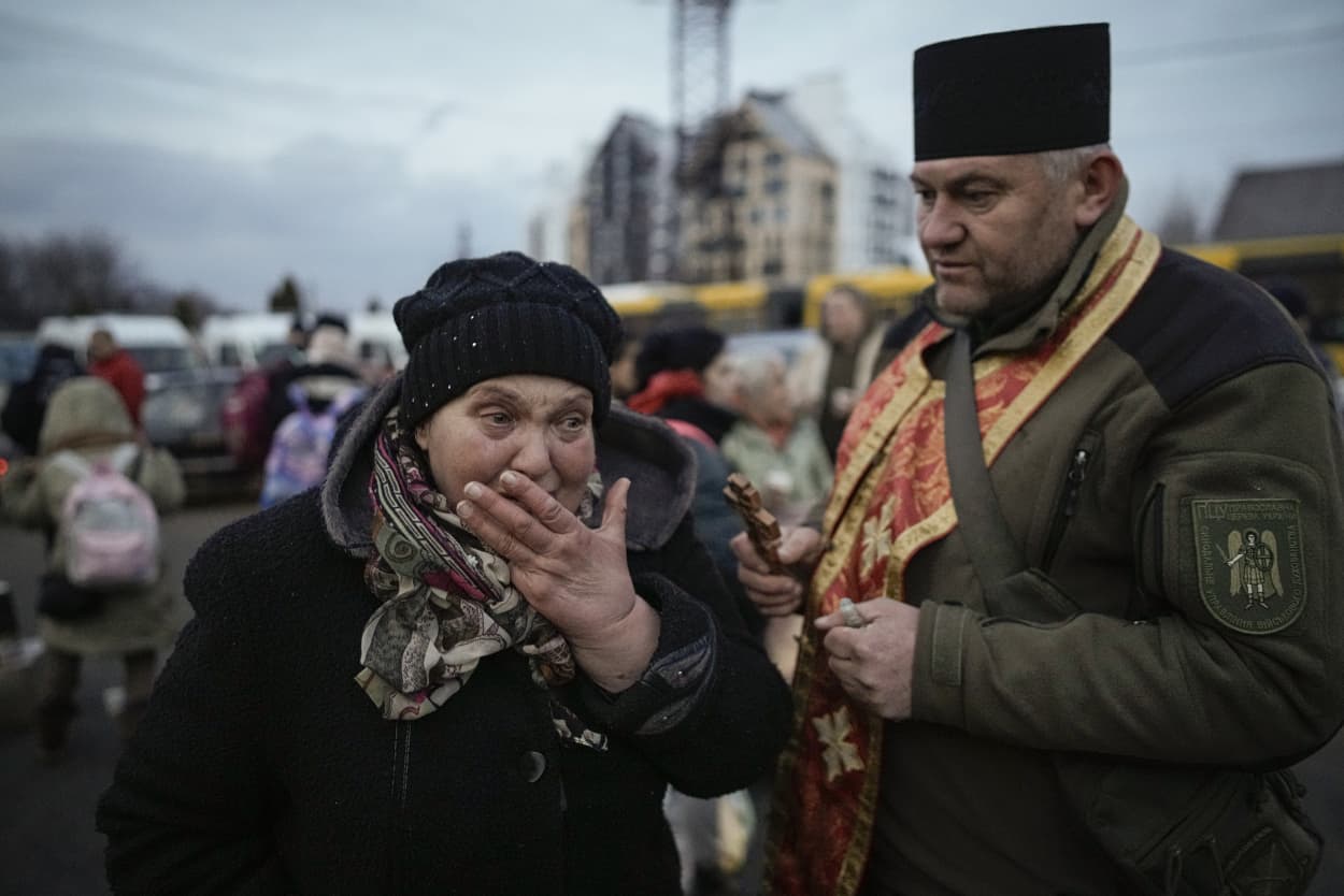 Image: military priest tries to comfort a crying woman in Irpin