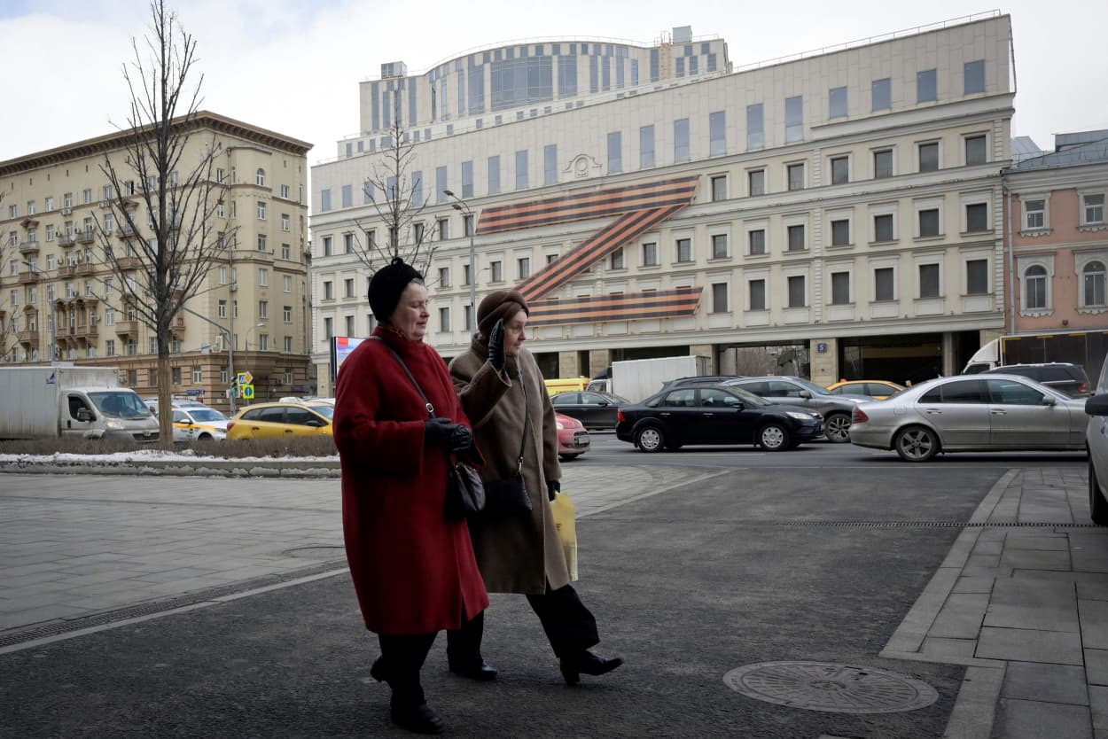 Women walk in front of a theatre adorned with the letter Z formed by a huge Russia's patriotic black and orange Saint George's ribbon in central Moscow on Wednesday.