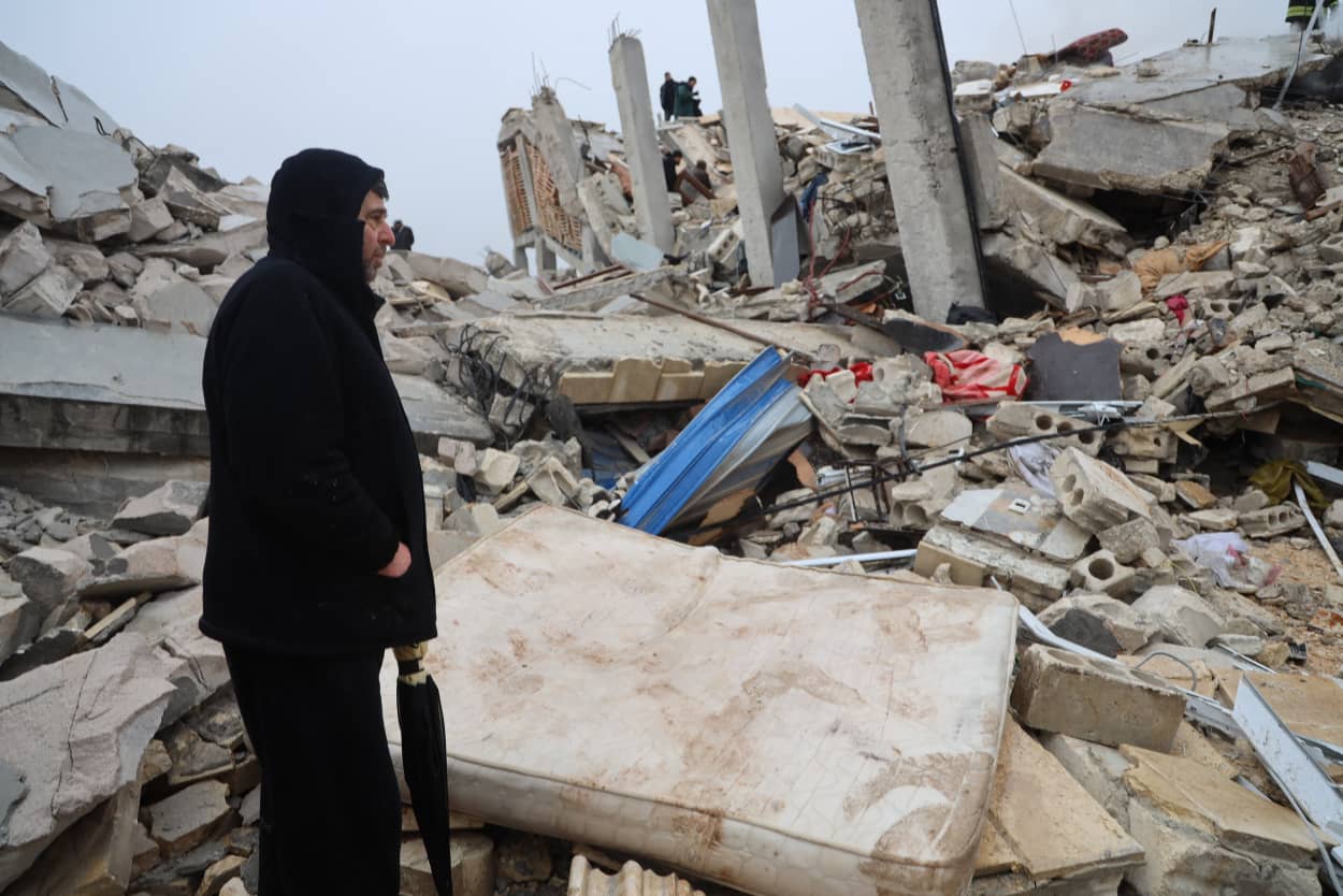 A man stands next to the rubble of a building in Zardana, Syria