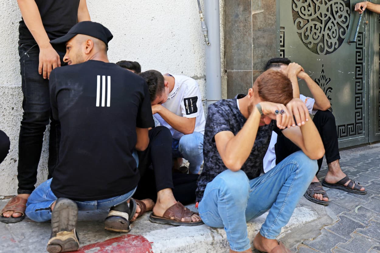 People cry on a stoop outside of a building in Gaza City