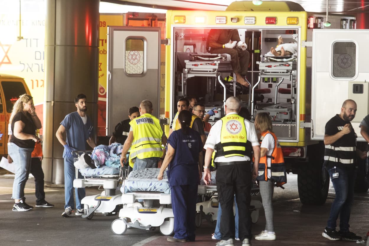 Emergency personnel work to transport injured soldiers from an ambulance