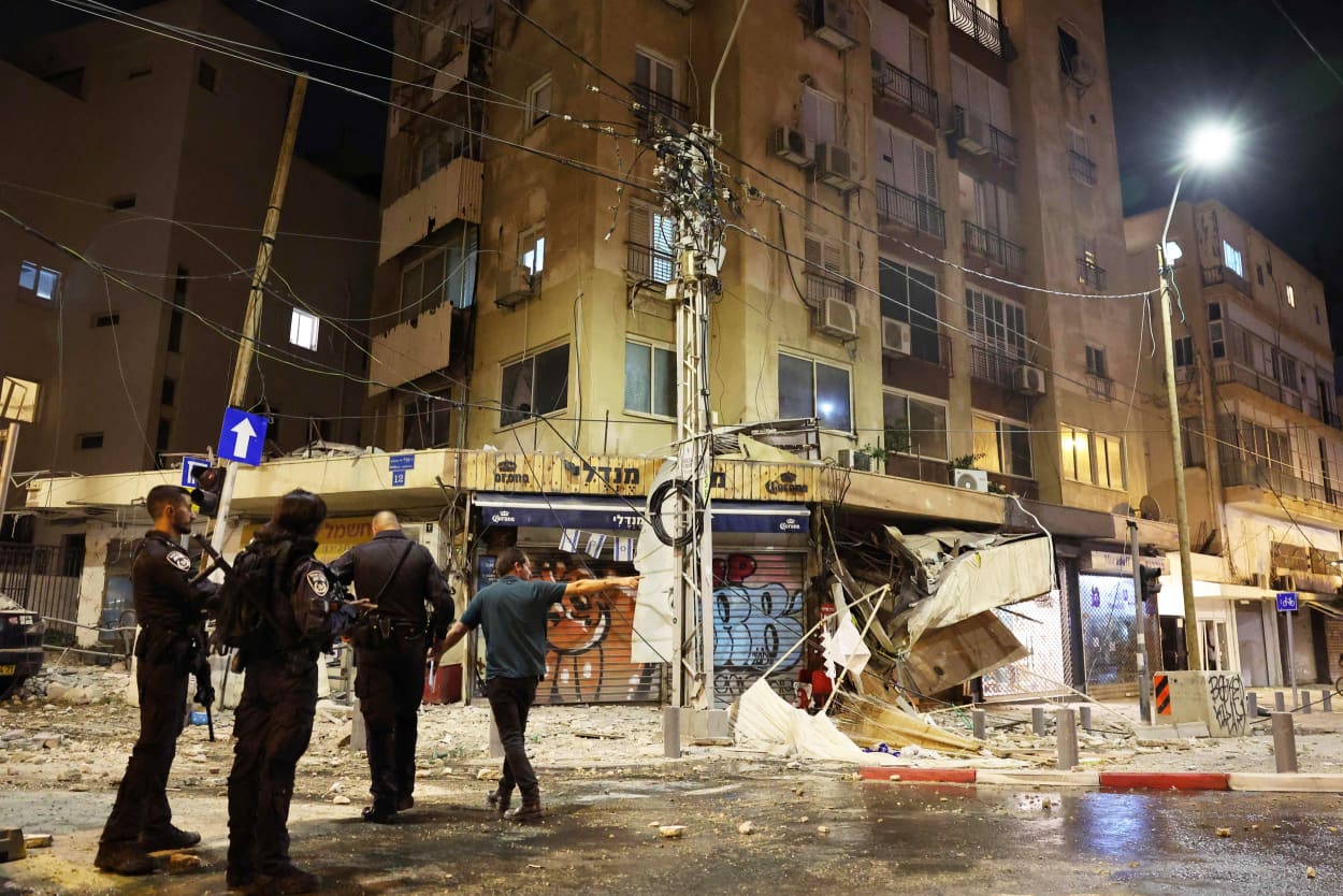 Officers gather in front of a damaged building on a Tel Aviv street