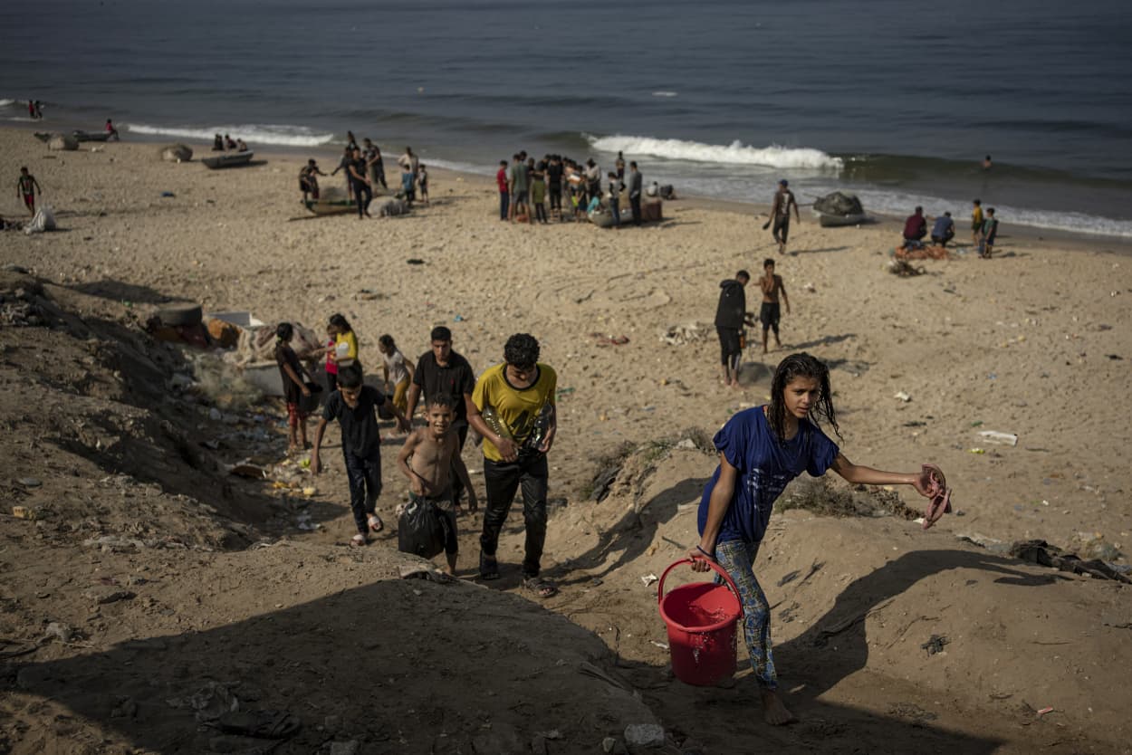 People carry seawater home from the beach in Deir al Balah, Gaza.