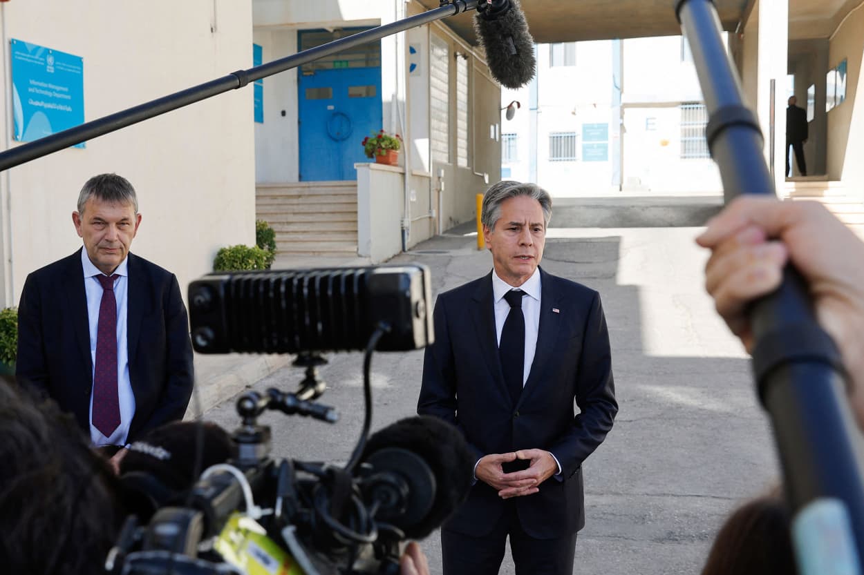 Antony Blinken speaks to press, who are holding boom microphones and gear