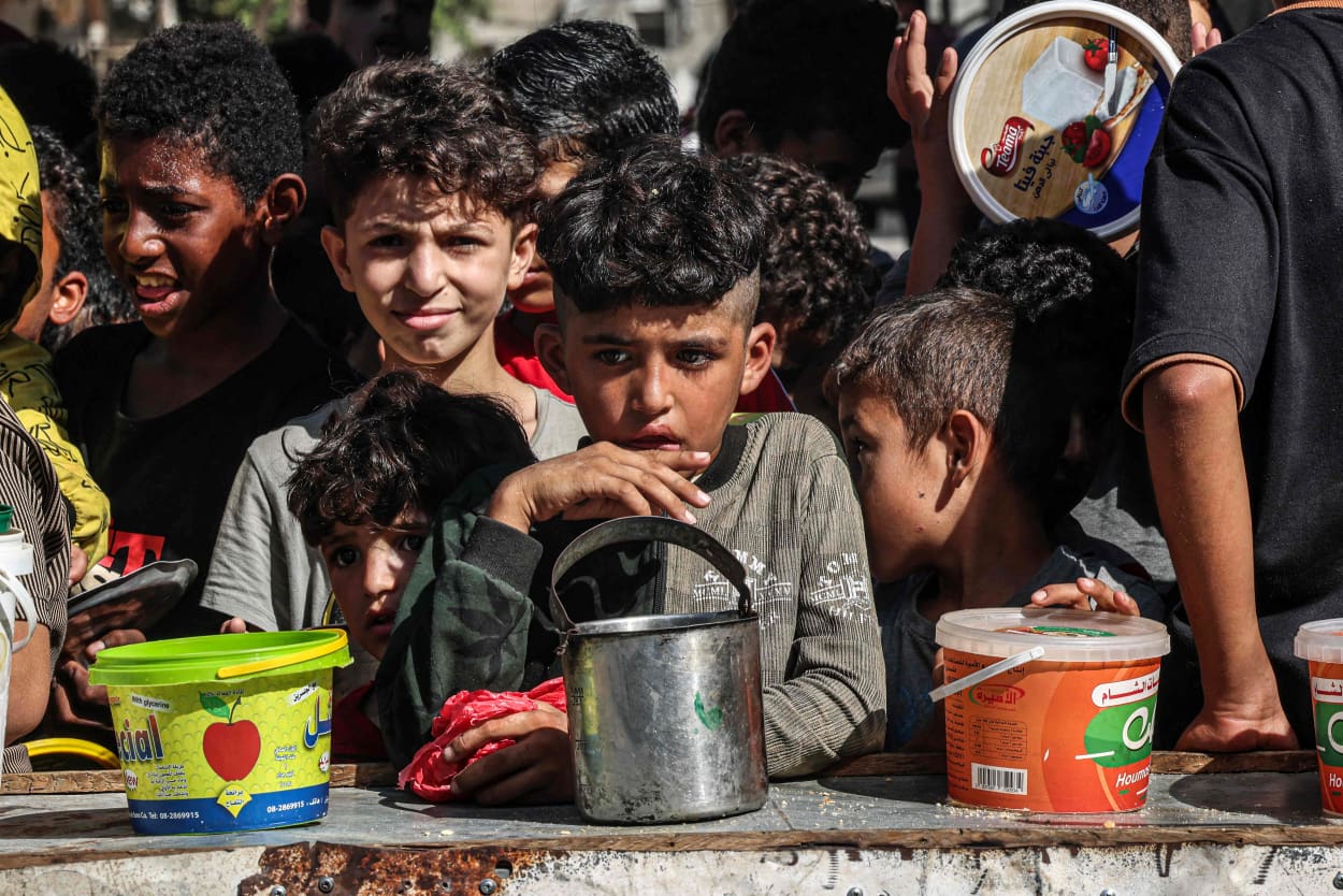 Children queue to receive a portion of food at a make-shift charity kitchen in Rafah in the southern Gaza Strip.