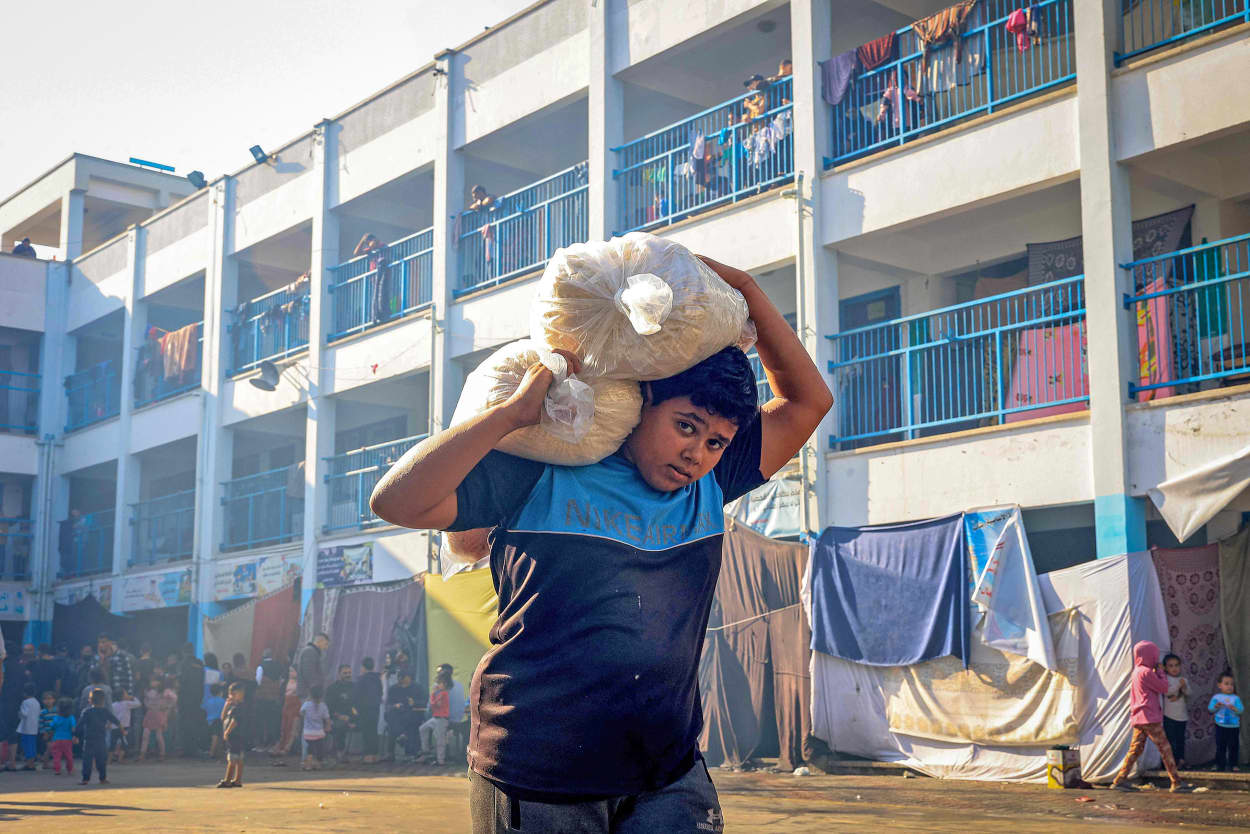 A boy walks with sacks of food supplies through at a school run by the United Nations Relief and Works Agency for Palestine Refugees in the Near East (UNRWA) in Rafah in the southern Gaza Strip on Nov. 14, 2023, where internally displaced Palestinians have taken refuge.