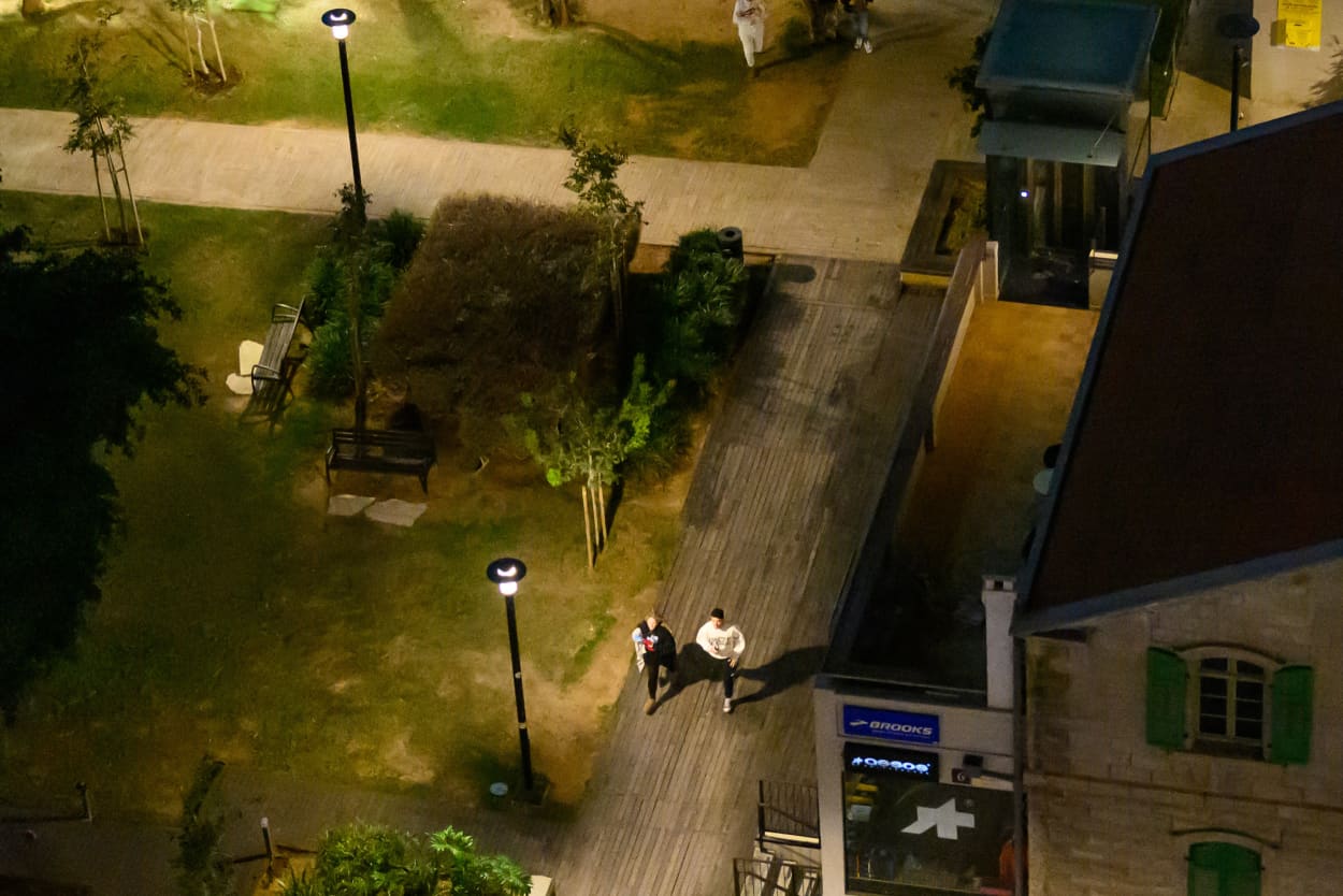 A wide shot of a courtyard in which two people run down a path into a market.