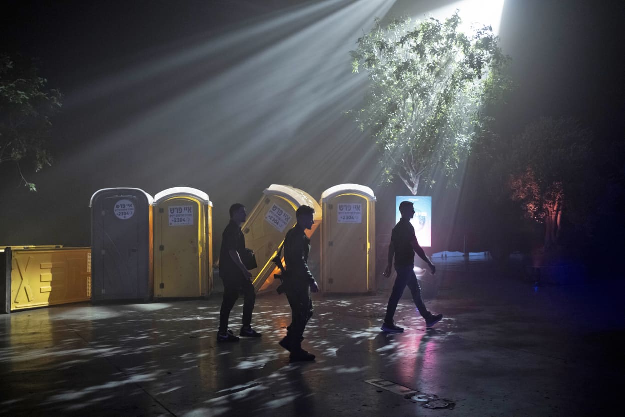 Security guards and a member of the Israeli security forces pass a display of toppled toilets during a press tour of the 06:29 memorial recreating the site of the Nova music festival where Hamas killed and kidnapped hundreds of revelers in an Oct. 7 cross-border attack, in Tel Aviv, Israel, Wednesday, Dec. 6, 2023.