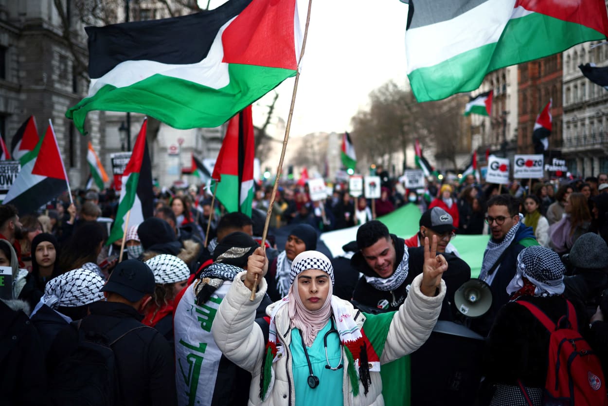 A large crowd of people with signs and flags march in the streets of London